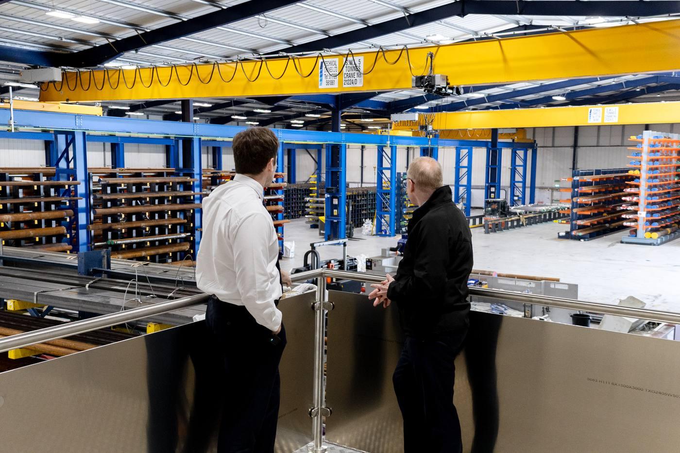 Two Parkside Steel managers overlooking the facility from mezzanine — warehouse with racking and overhead crane visible