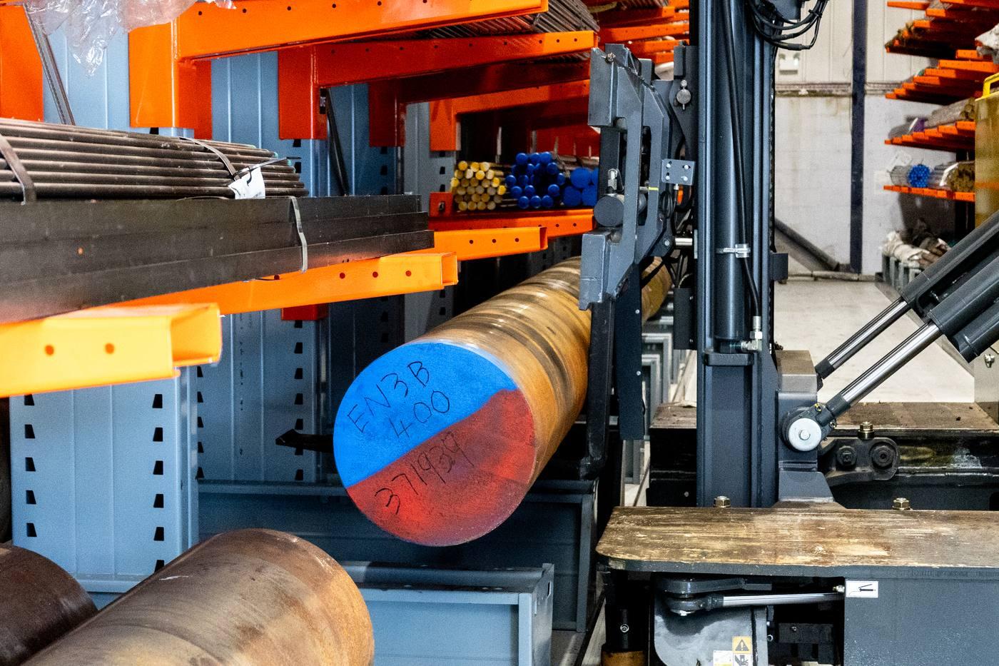 EN3B 400mm black round bar on Combilift forks — blue/red colour-coded end, orange racking behind