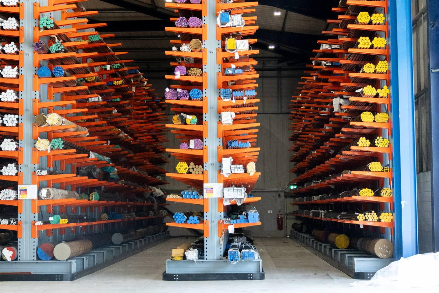 Three towers of orange cantilever racking fully loaded with colour-coded engineering steel bar in all grades and sizes
