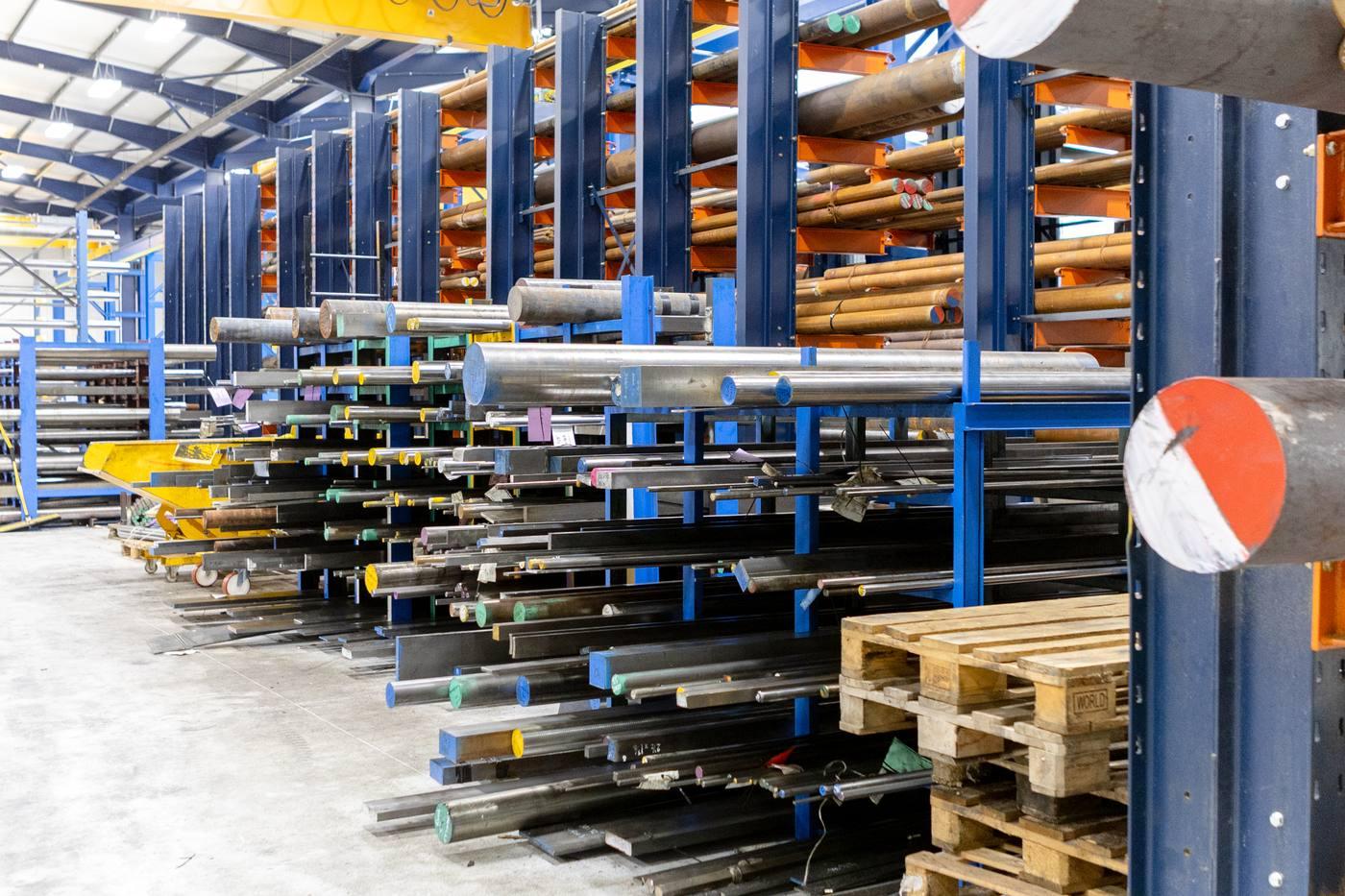 Mixed stock in blue cantilever racking — bright bar, flat bar and square bar with colour-coded grade identification