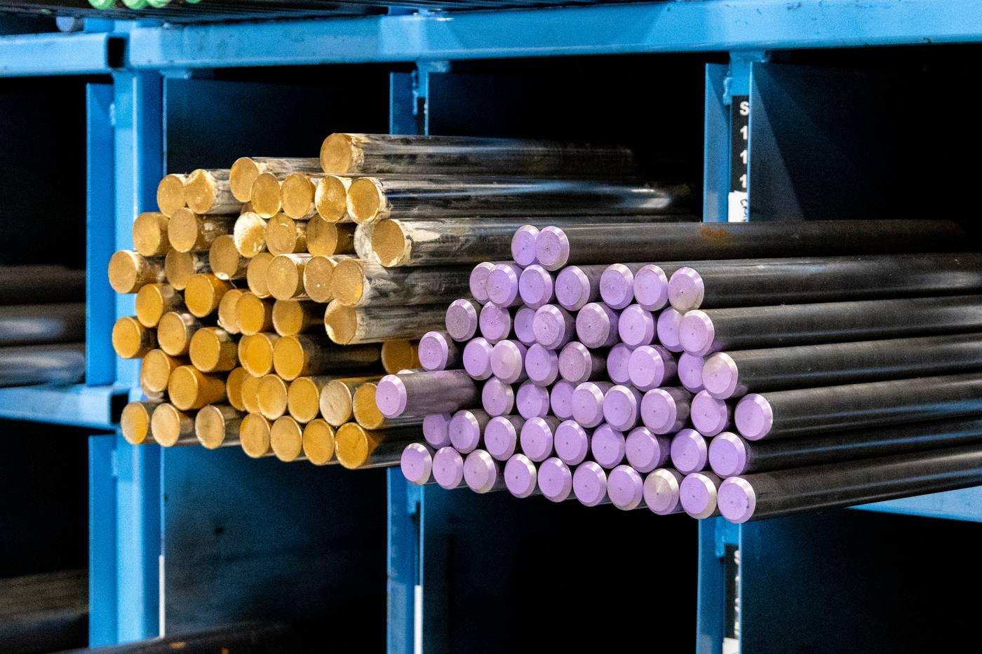 Colour-coded bar ends in blue racking — yellow and purple grade identification showing range of carbon steel grades