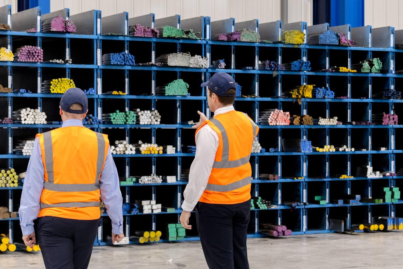 Two Parkside Steel team members reviewing the colour-coded engineering steel bar range in blue cantilever racking