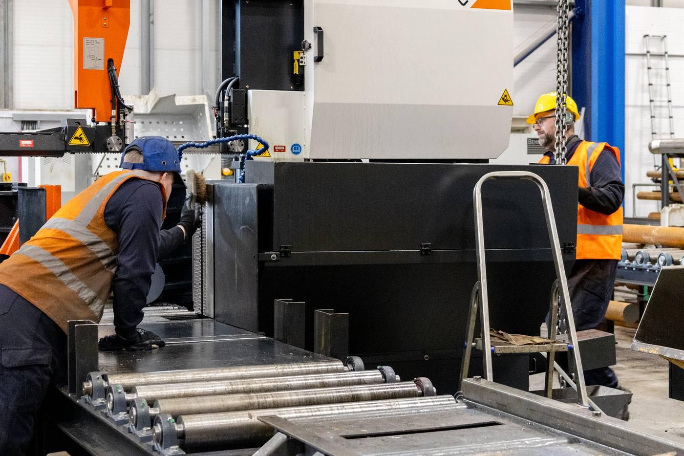 Two operatives at large COSEN band saw — one cleaning, one operating