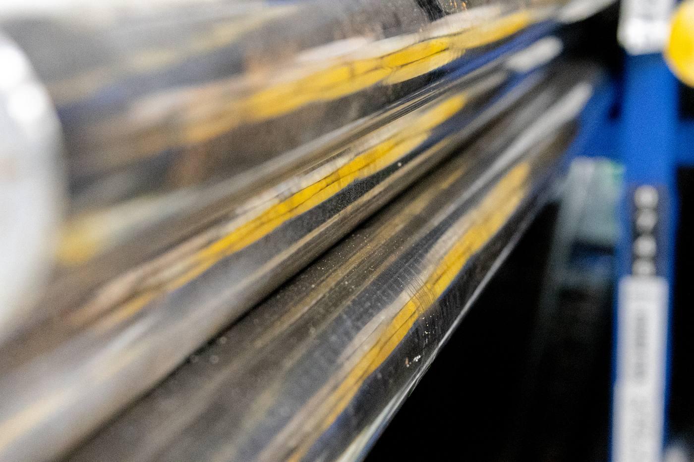 Macro side-on shot of bright bar — smooth drawn surface with yellow protective wrapping